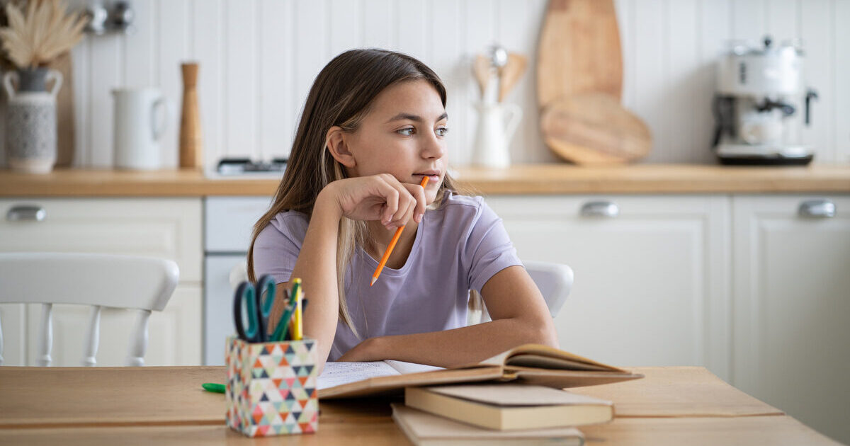 girl looking thoughtfully to one side at kitchen table